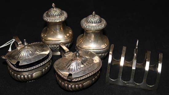 Four silver condiments and a silver toast rack.